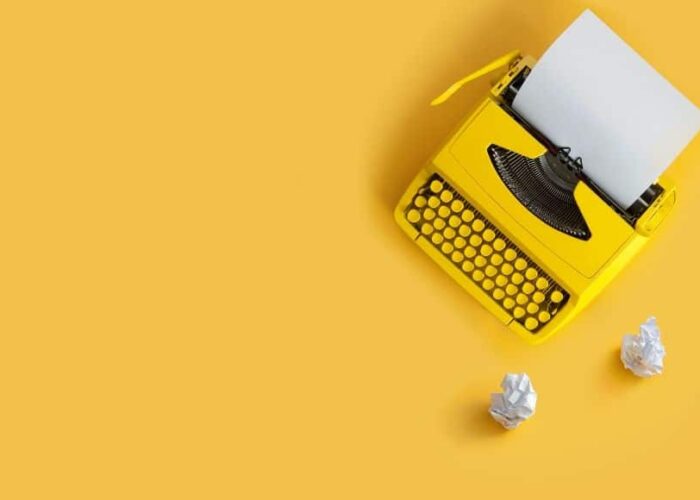 machine à écrire sur fond jaune avec des morceaux de papier
