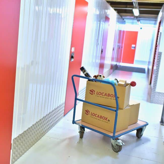 Chariot avec des cartons Locabox dans le couloir d'un centre de stockage
